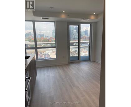 A spacious room with a view of the cityscape through large windows.