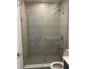 A bathroom with a toilet, a glass shower stall and a white door.