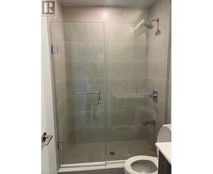 A bathroom with a toilet, a glass shower stall and a white door.