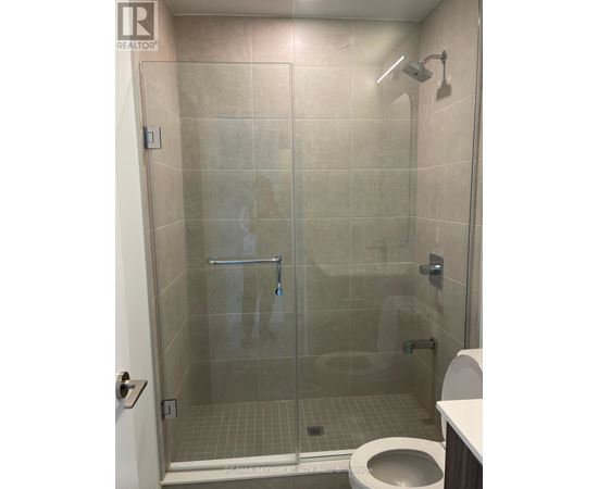 A bathroom with a toilet, a glass shower stall and a white door.