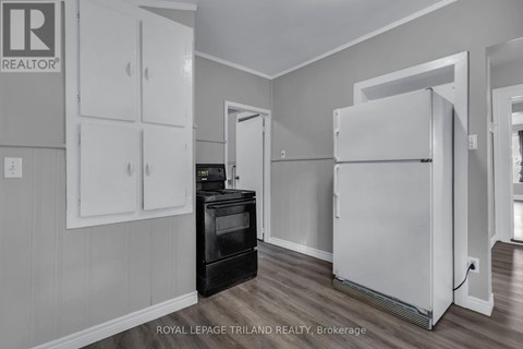 A white refrigerator in a kitchen with a black stove and cabinets.