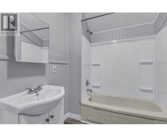 A white bathroom with a sink, mirror, and bathtub.