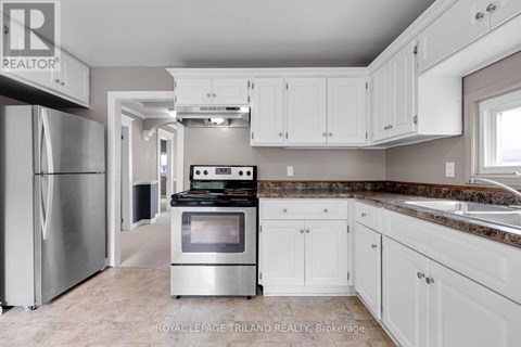 A kitchen with a stainless steel refrigerator and white cabinets.