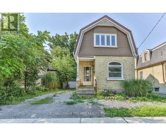A house with a brown roof and a gravel driveway in front.