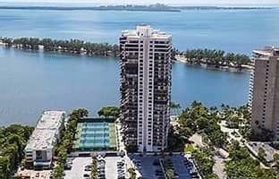 A tall white building with a pool in front of it.