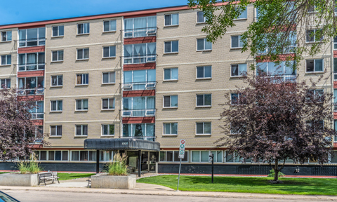 A large apartment building with a tree in front.