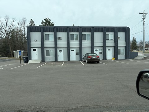 A parking lot with a building and a car.