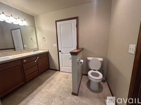 A bathroom with a toilet, sink, and mirror.