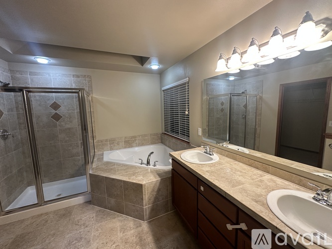 A modern bathroom with a large tub and double sinks.