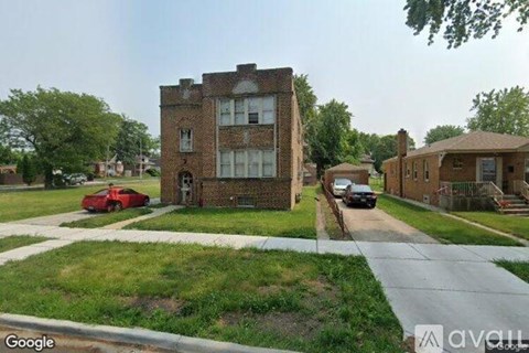 A red car is parked in front of a brick building.