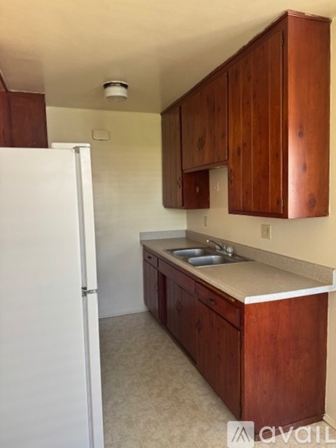 A kitchen with wooden cabinets and a white refrigerator.