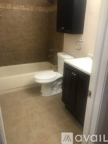 A white toilet sits in a bathroom next to a bathtub.