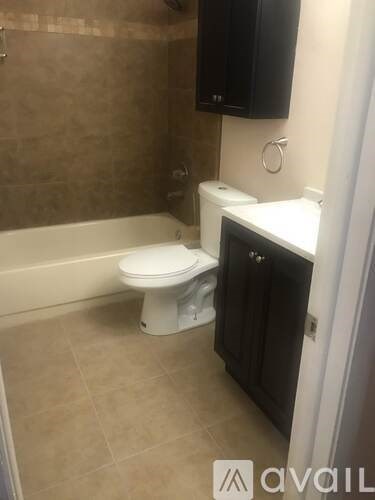 A white toilet sits in a bathroom next to a bathtub.