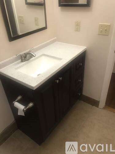 A bathroom sink with a black cabinet and a mirror above it.