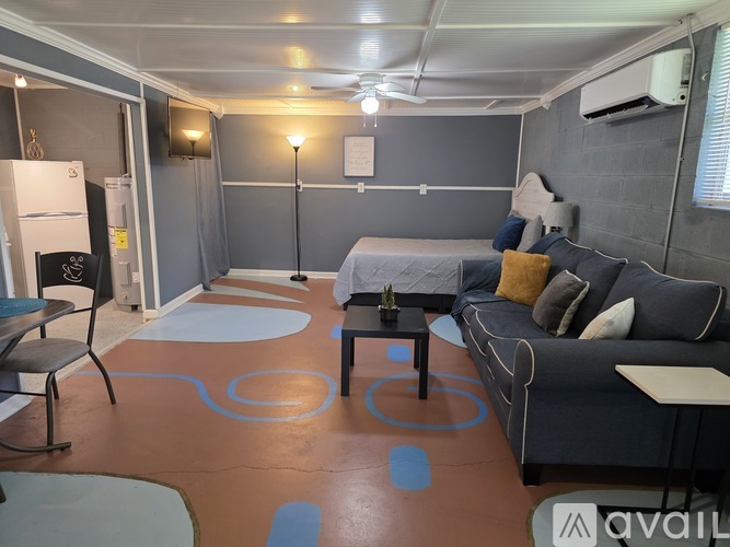 A living room with a grey couch, a black chair, and a white fridge.