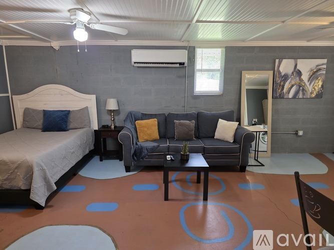 A bedroom with a bed, couch, and a fan.