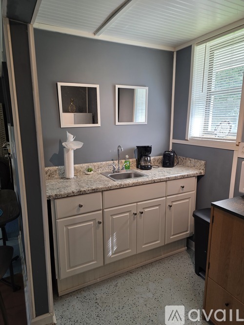A kitchen with a sink, cabinets, and a window.