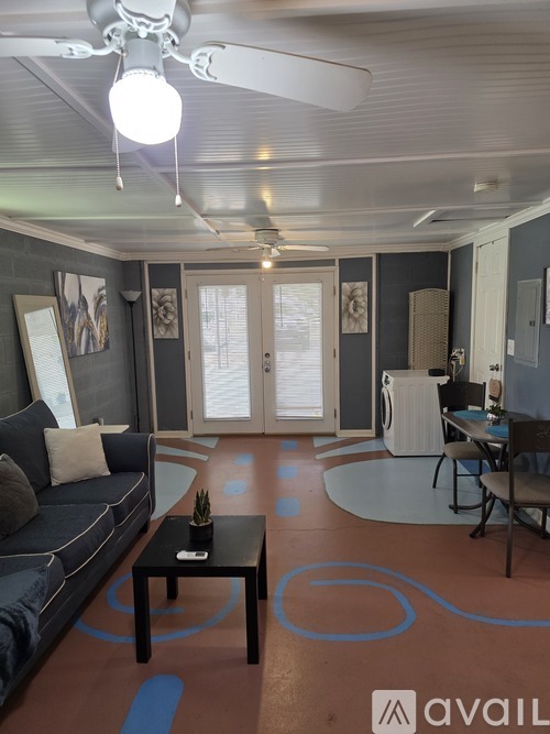 A living room with a grey couch and a ceiling fan.