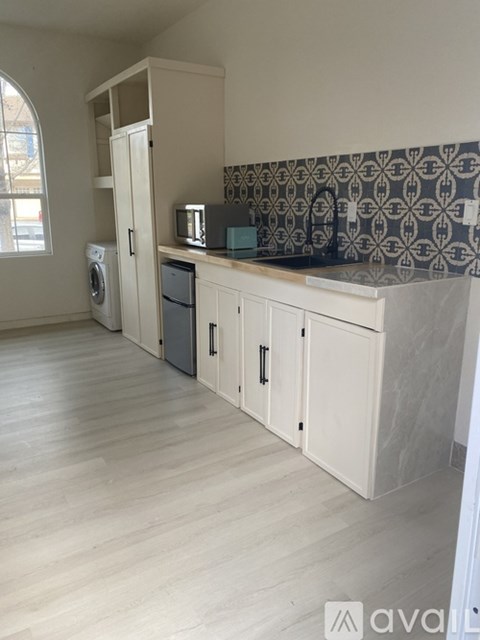 A kitchen with a washing machine and a microwave on the counter.