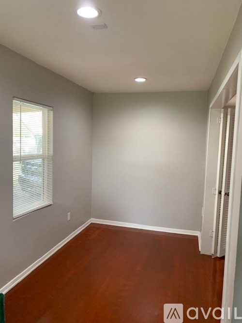 A room with wooden floors and a window with blinds.
