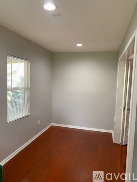A room with wooden floors and a window with blinds.