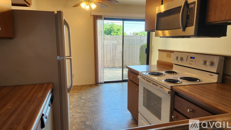 A kitchen with a refrigerator, microwave, oven, and a wooden counter.