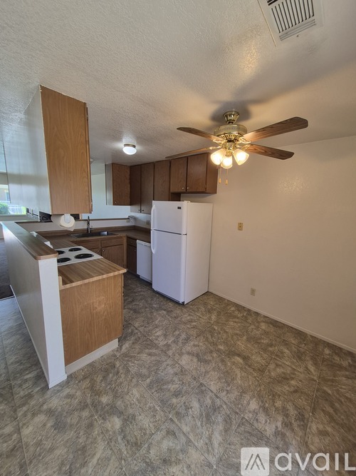 A kitchen with a white refrigerator and wooden cabinets.