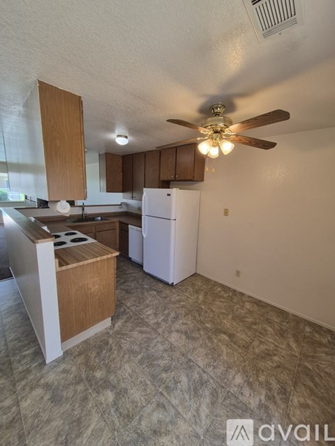 A kitchen with a white refrigerator and wooden cabinets.