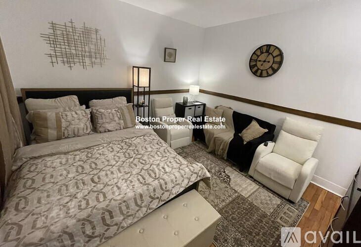 A bedroom with a large bed and a white chair.