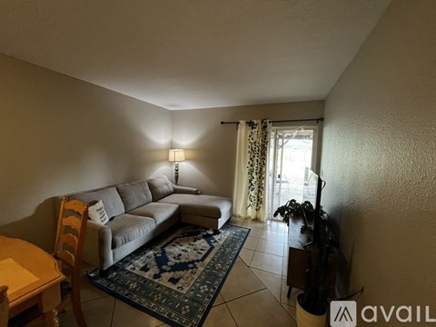 A living room with a grey couch and a blue patterned rug.