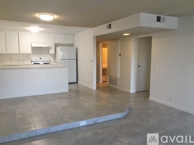 A kitchen with white cabinets and a white fridge with a countertop and a sink.