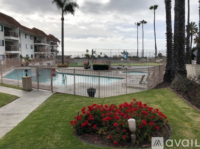 A pool surrounded by a fence and a flower bed.