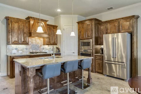 A kitchen with wooden cabinets and a marble island.