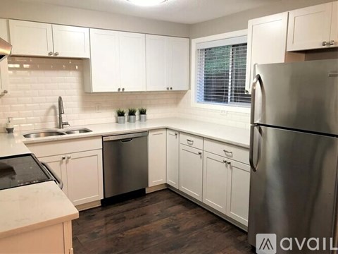 A kitchen with white cabinets and a stainless steel refrigerator.
