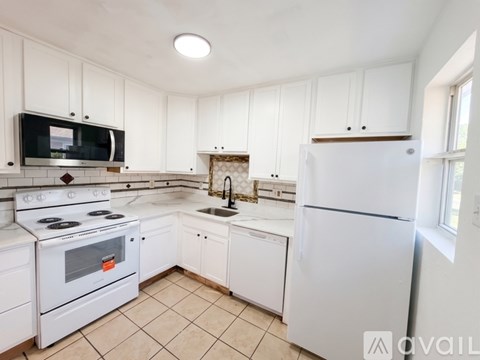 A kitchen with white cabinets and appliances.