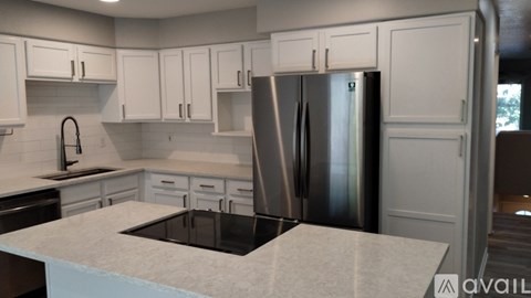A kitchen with white cabinets and a stainless steel refrigerator.