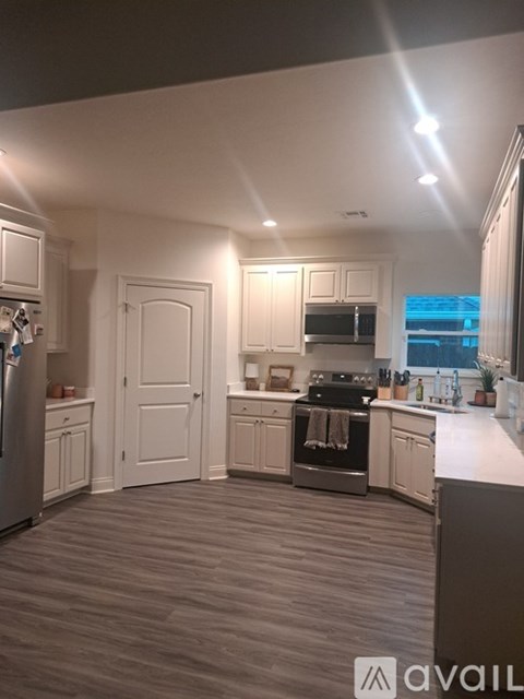 A kitchen with white cabinets and a wooden floor.