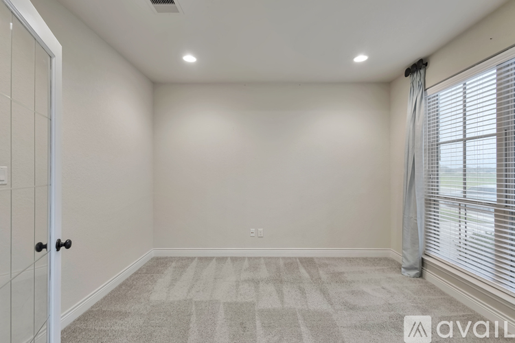 A room with a carpeted floor and a window with blinds.