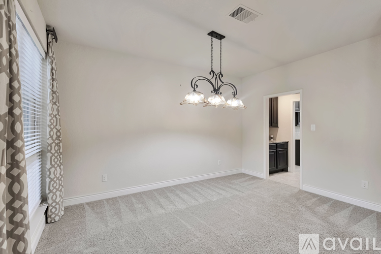 A spacious room with a chandelier and patterned carpet.