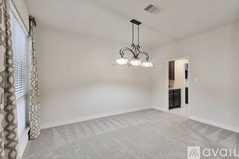 A spacious room with a chandelier and patterned carpet.