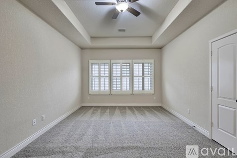 A room with a carpeted floor and a ceiling fan.