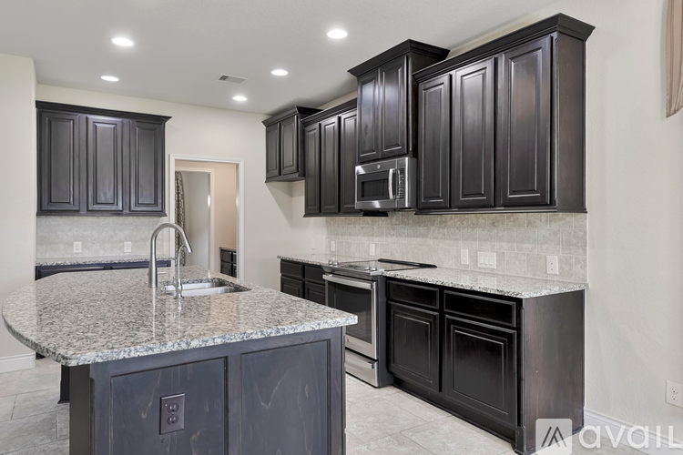 A kitchen with dark cabinets and granite countertops.