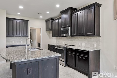 A kitchen with dark cabinets and granite countertops.