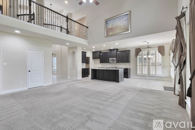 A spacious living room with a grey carpet and a painting on the wall.