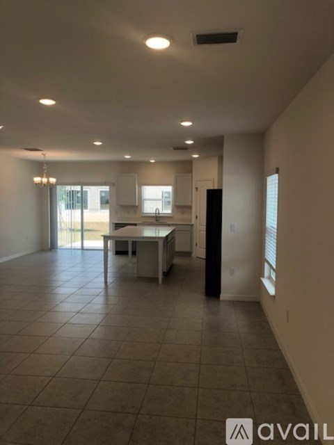 A spacious room with tiled flooring and a kitchen area with a table and chairs.