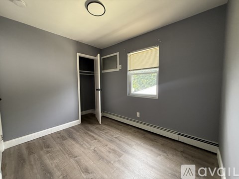 A room with a grey wall and a window with blinds.