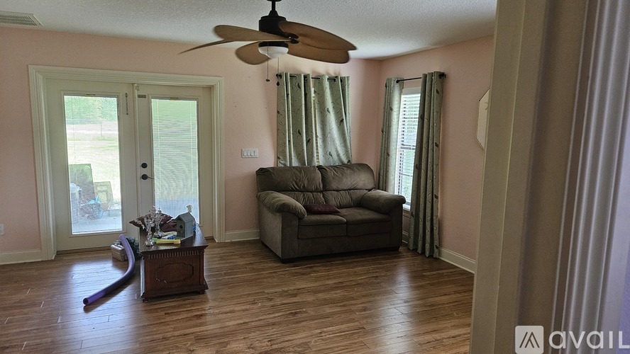 A living room with a brown couch and a ceiling fan.