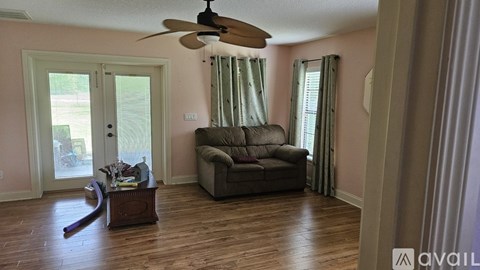 A living room with a brown couch and a ceiling fan.