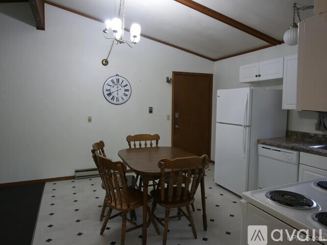 A kitchen with a table and chairs and a clock on the wall.