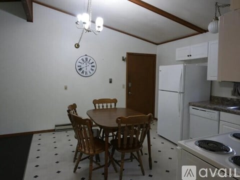 A kitchen with a table and chairs and a clock on the wall.